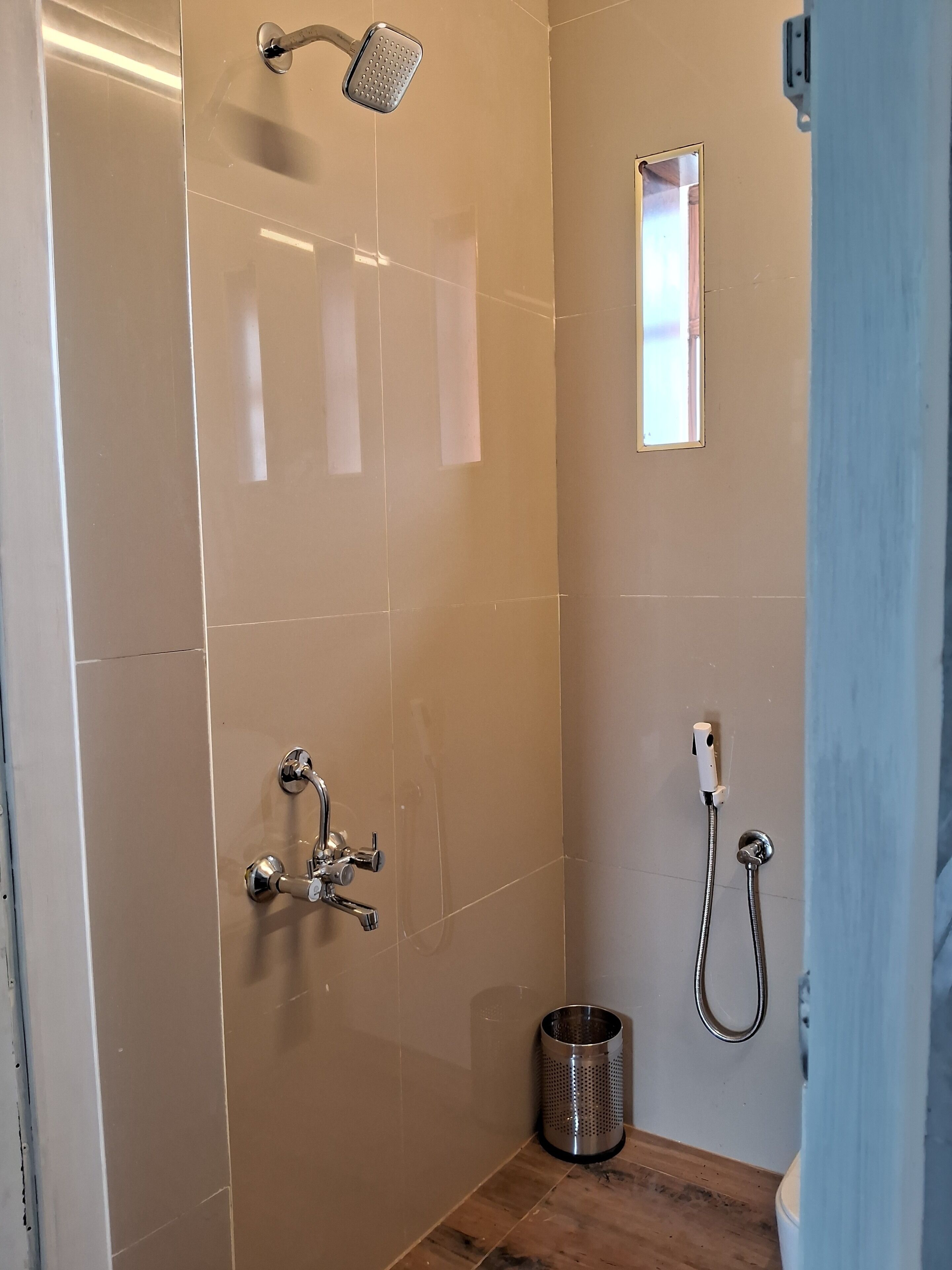 A modern shower area with a handheld showerhead, a wall-mounted faucet, and a handheld shower hose.