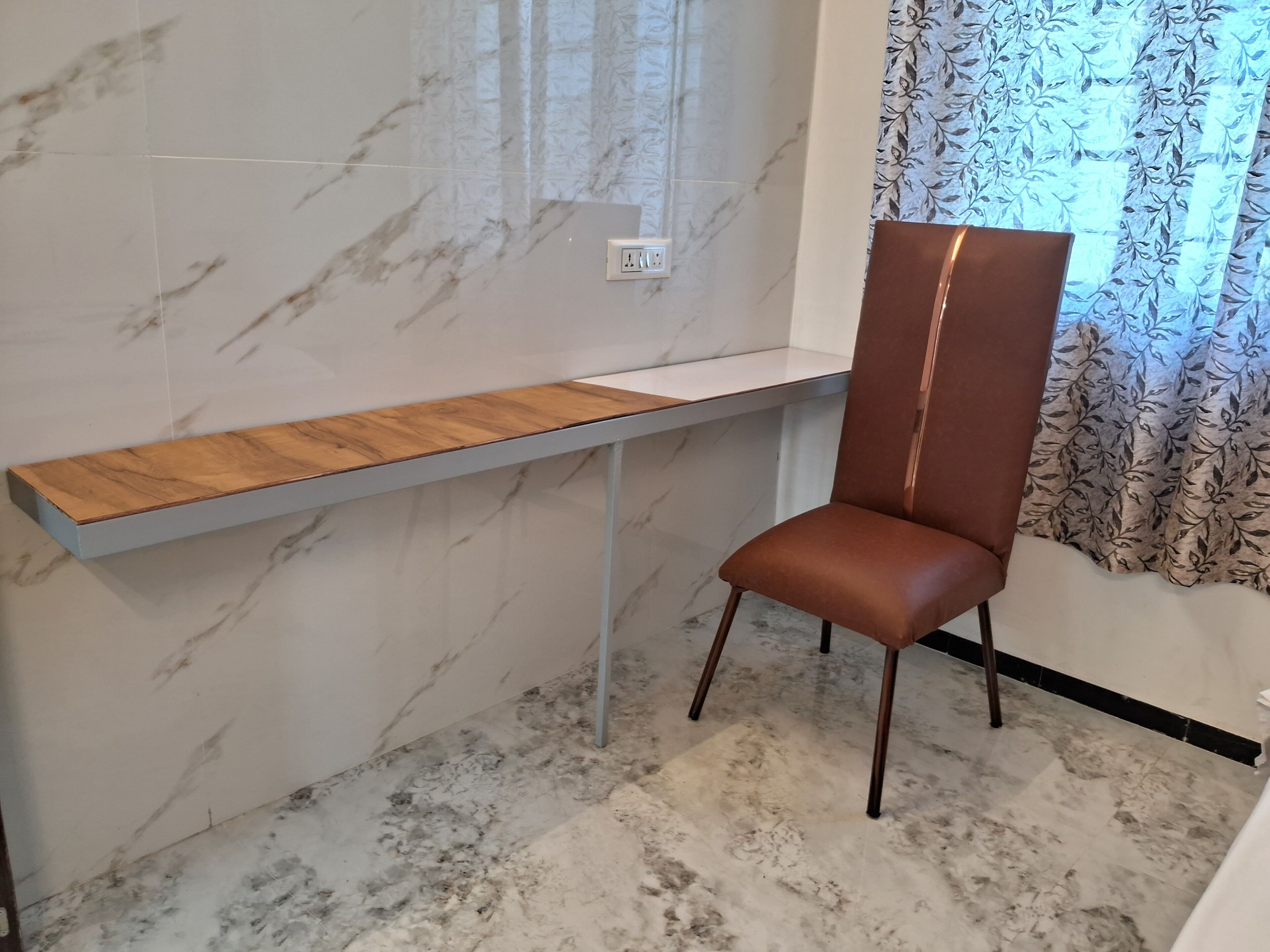 Une chambre moderne avec un sol en marbre, un bureau en bois, un fauteuil en cuir marron et un rideau à motifs.