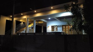 A modern house with a staircase, a car parked in the driveway, and a tree in the foreground. - Luxury 2-bedroom apartment with WiFi, AC & Rooftop Jacuzzi pool near Kanyakumari (Suchindram)