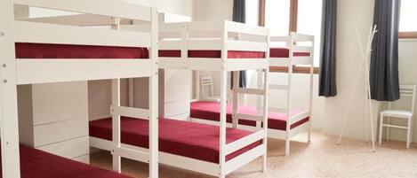Des lits superposés dans une chambre avec une fenêtre et une chaise.