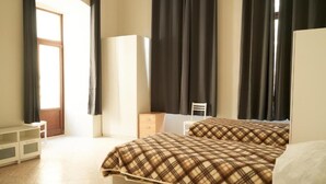Een slaapkamer met een bed, een kledingkast, een bureau en een raam met gordijnen.