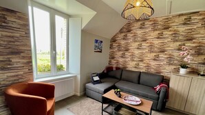A modern living room with a grey sofa, a red armchair, a wooden coffee table, and a unique geometric pendant light.
