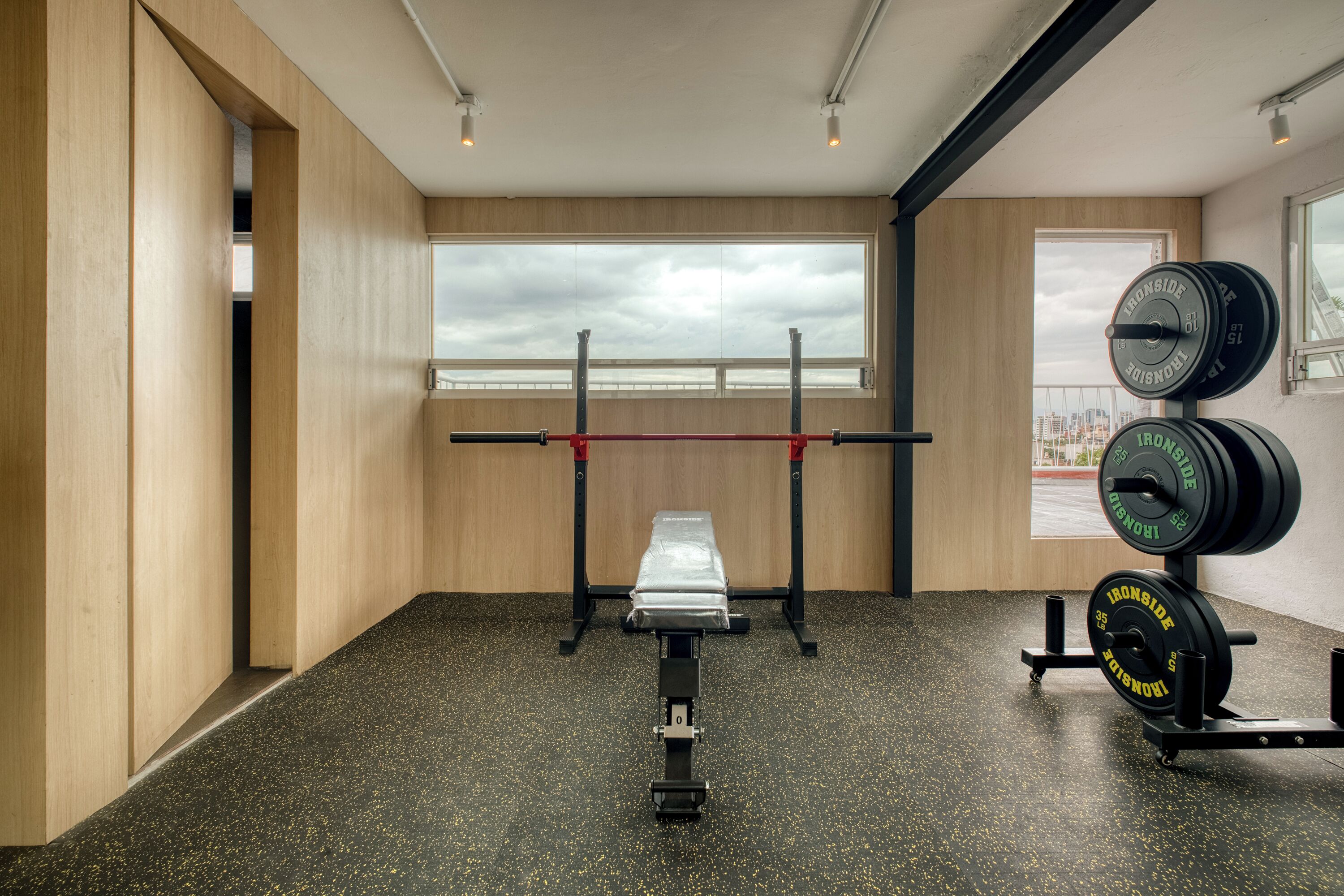 Une salle de sport équipée d’un banc de développé couché, d’un support à squats et de poids.