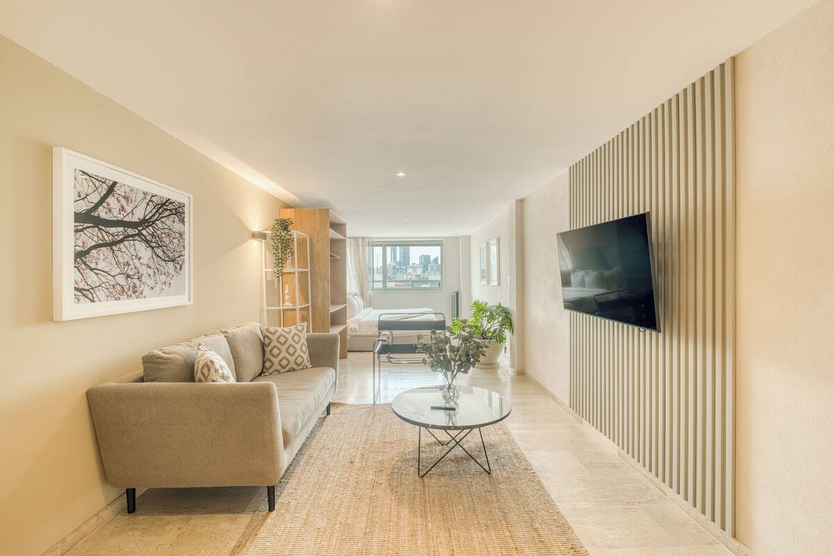 Een moderne woonkamer met een bank, een salontafel en een tv aan de muur.