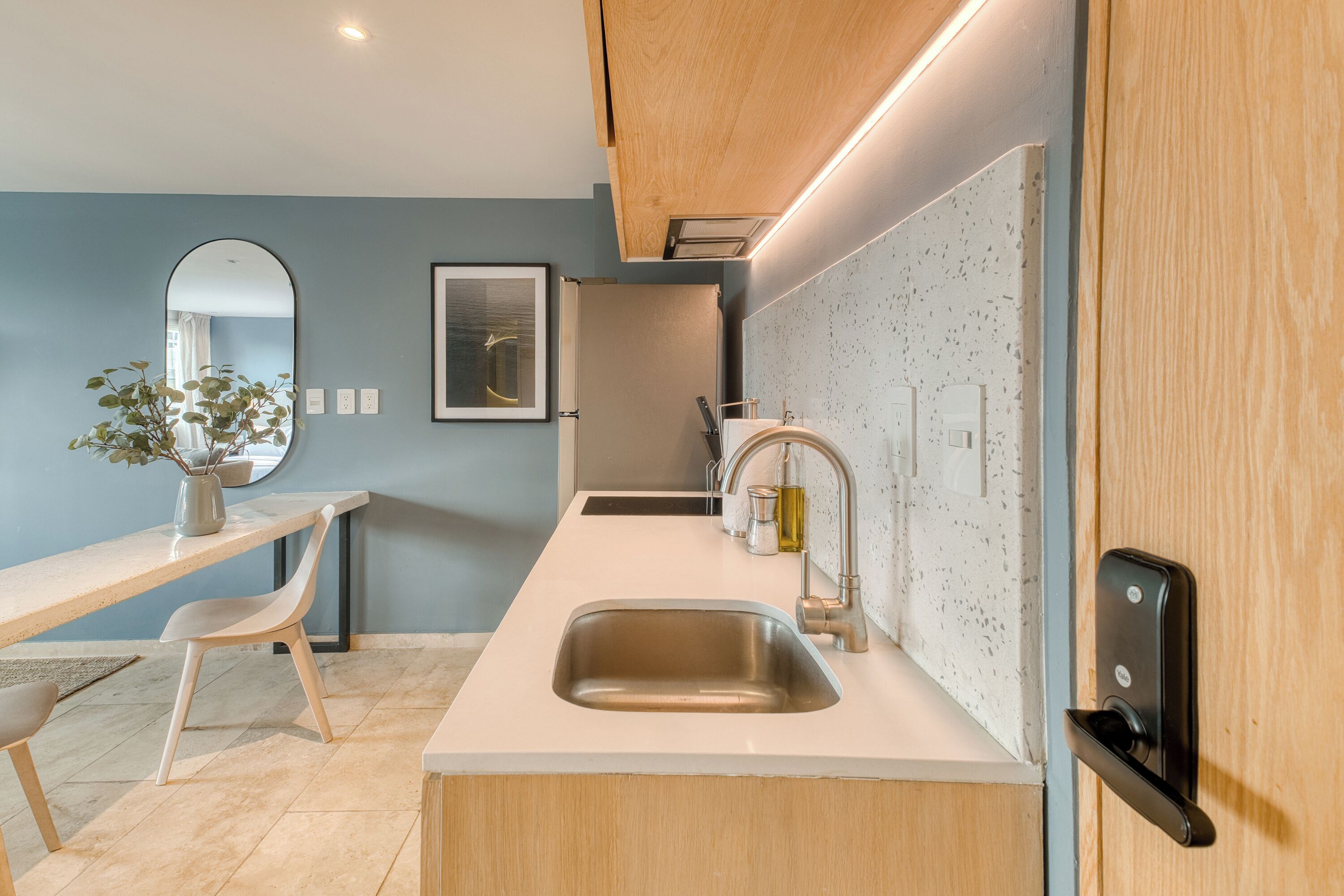 A modern kitchen with a sink, countertop, and wooden cabinets.