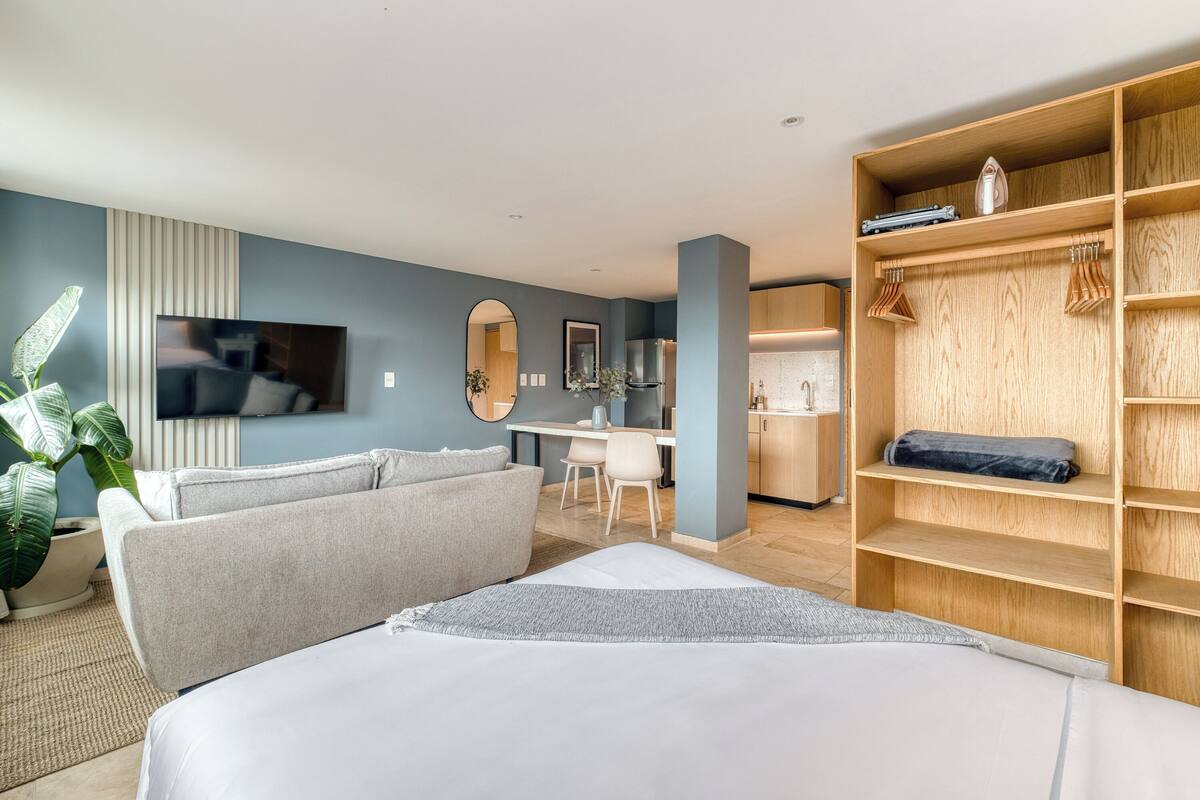 Een moderne hotelkamer met een bed, een bank, een televisie, een bureau en een kledingkast.