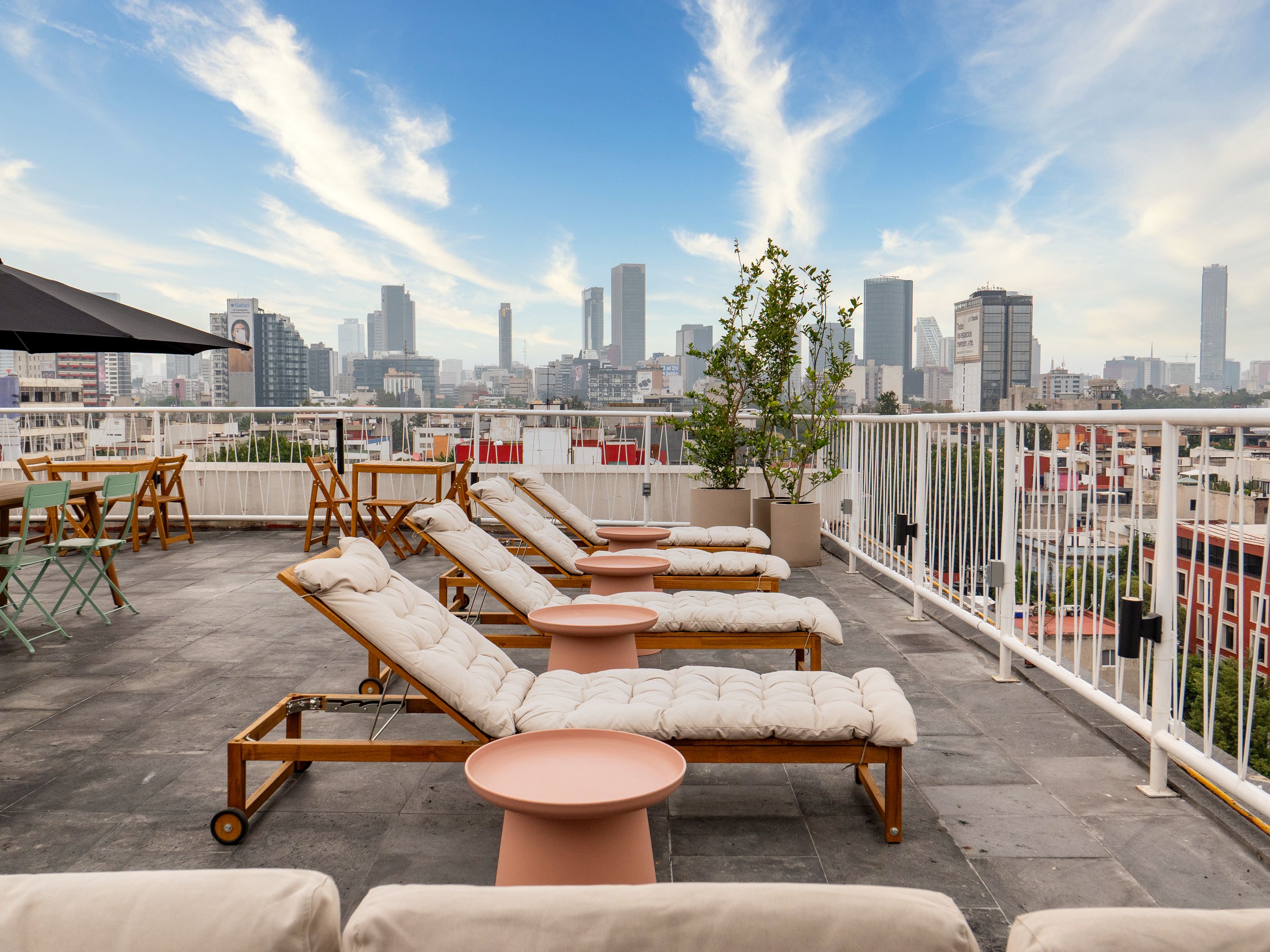 Eine Dachterrasse mit Lounge-Möbeln, Tischen und Topfpflanzen.