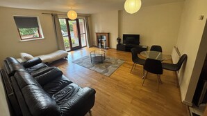 A living room with a leather sofa, a glass coffee table, a TV, and a fireplace.