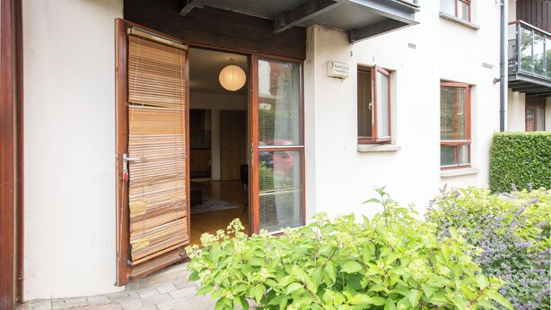 A building entrance with a wooden door, a sign above the door, and a small balcony on the right side.