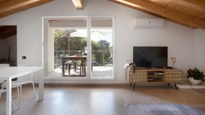 A modern living room with a TV, a dining table, and a balcony with outdoor furniture. - Apartment 'La Terrazza di Elisabetta' with Private Terrace, Balcony and Air Conditioning (Viareggio)