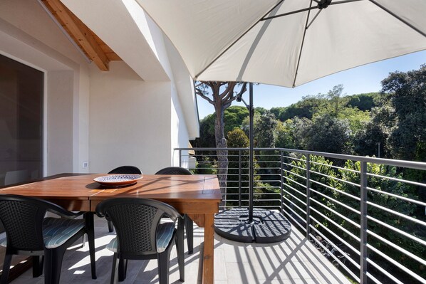 A balcony with a wooden table, two chairs, and a large umbrella.