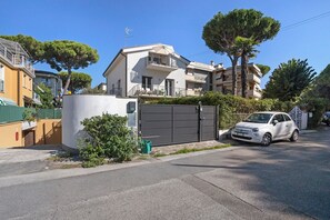 A residential building with a gated entrance, a balcony, and a parked car.