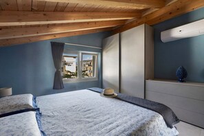 A bedroom with a bed, a window with curtains, a dresser, and an air conditioning unit.