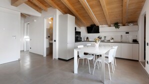 A modern kitchen with white cabinetry, a dining table with white chairs, and a wooden ceiling. - Apartment 'La Terrazza di Elisabetta' with Private Terrace, Balcony and Air Conditioning (Viareggio)