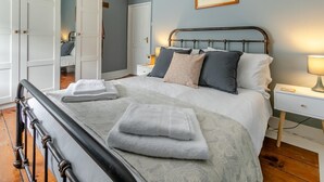A neatly made bed with folded towels, a bedside lamp, and a framed picture on the wall. - 2 Bed in Ilfracombe (oc-f31994) (Ilfracombe)