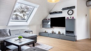 Un salon moderne doté d’une verrière, de canapés gris, d’un téléviseur à écran plat et d’un design minimaliste.