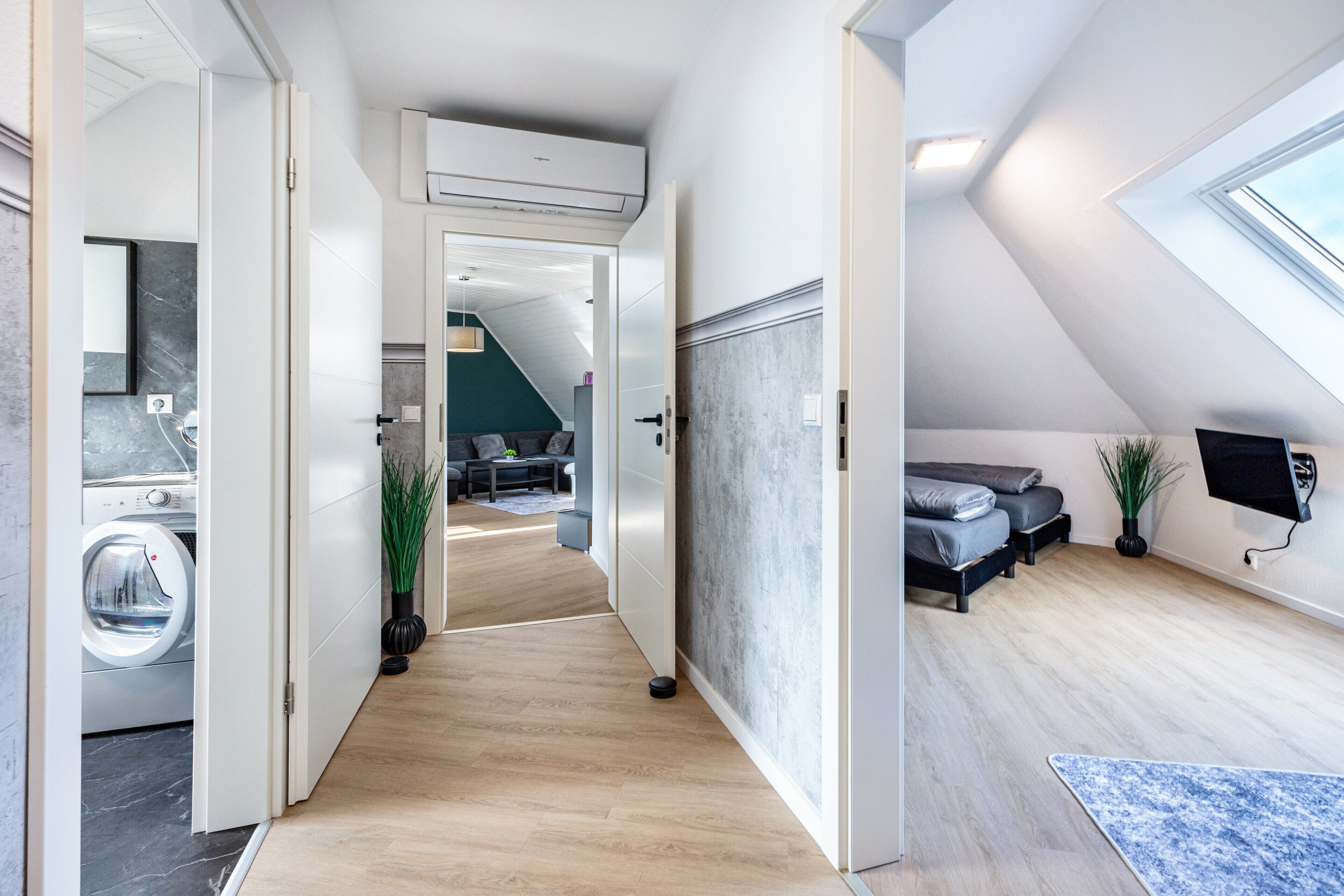 En moderne lejlighed med vaskerum, stue med sofa og fjernsyn, samt soveværelse med seng.