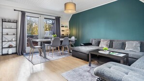 Un salon moderne comprenant un coin repas, un canapé, une table basse et une bibliothèque.