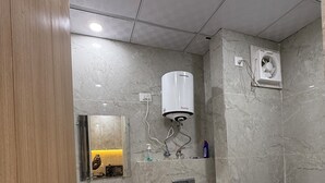 A modern bathroom with a sink, toilet, and a wall-mounted water heater.