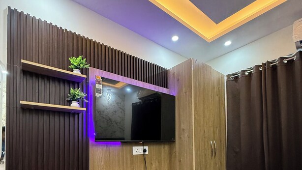 A modern bedroom with a built-in TV, wooden storage, and a bed.