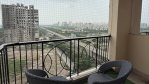 A balcony with two wicker chairs and a view of a cityscape.