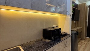 A modern kitchen with grey marble cabinets, a black countertop, and a built-in oven.