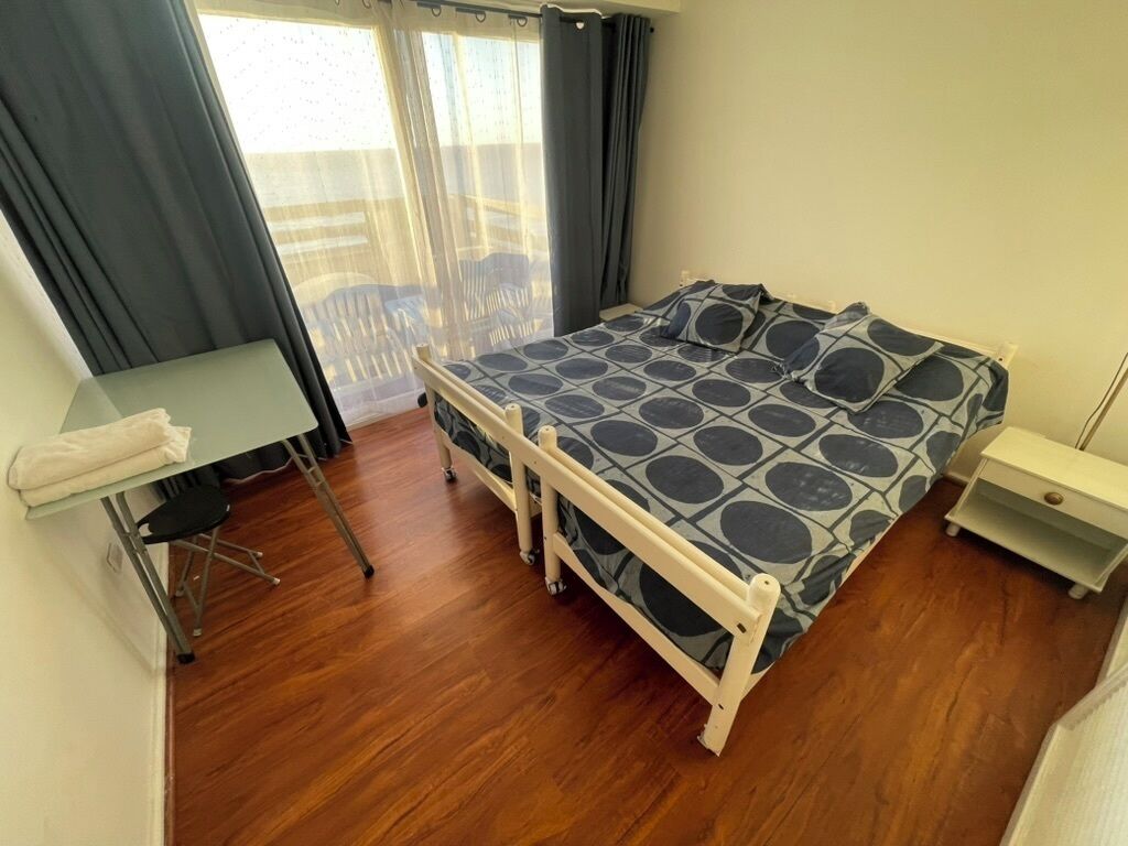 A compact room with a bed, a small table, and a chair.