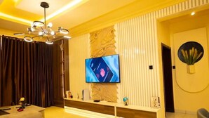 Ein modernes Wohnzimmer mit Flachbildfernseher an der Wand, einer Couch und einem Couchtisch.