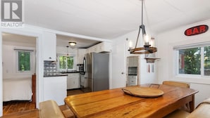 A spacious kitchen with white cabinets, a large wooden dining table, and a bar sign. - Hennessy Lake House, Port Carling Waterfront Property (Port Carling)