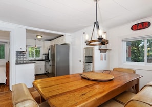 Une cuisine spacieuse avec des meubles blancs, une grande table à manger en bois et un panneau décoratif de bar.