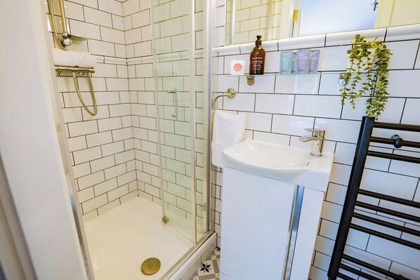 A bathroom with a glass-enclosed shower, a white sink, and a towel rack. - Charming Howth Marina Retreat (Dublin)