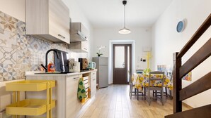 Una cocina con un carrito amarillo, una mesa de comedor con sillas, un refrigerador y un microondas.