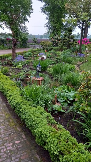 A garden with a variety of plants, a lamp post, and a brick pathway. - Holiday Home 'Ruhe Auf Dem Lande' with Private Terrace and Private Garden (Westerstede)
