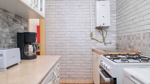 A compact kitchen with a gas stove, a coffee maker, and a built-in oven. - Cozy Studio in Katowice | Balcony and Wi-Fi (Katowice)
