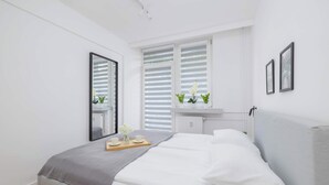 Quarto moderno com cama, mesa de cabeceira com bandeja e janela com persianas.