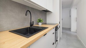 Uma cozinha moderna com pia preta, bancada de madeira e uma pequena planta em vaso.