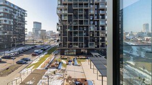 Un immeuble de grande hauteur doté de nombreux balcons, un parking rempli de voitures et une vue sur le paysage urbain.