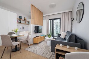Ein modernes Wohnzimmer mit einer Couch, einem Esstisch und einem Fernseher.