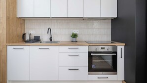 Une cuisine moderne avec des armoires blanches, un four en acier inoxydable et un plan de travail en bois.