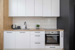 Eine moderne Küche mit weißen Schränken, einem Edelstahlbackofen und einer Holz Arbeitsplatte.