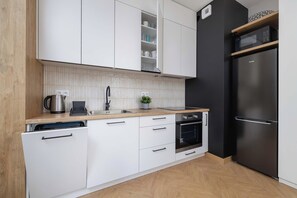 Una cocina moderna con armarios blancos, un refrigerador negro y una encimera de madera.