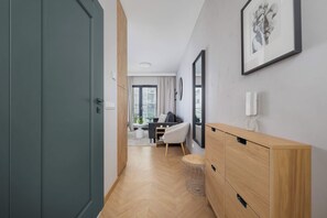 Een moderne hotelkamer met een houten vloer, een bureau met stoel, een grote spiegel en een garderobekast.