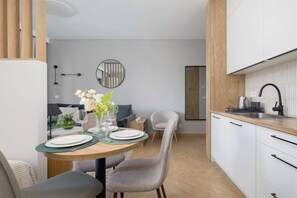 Une cuisine moderne avec des meubles blancs, un plan de travail en bois et un coin repas comprenant une table ronde et des chaises.