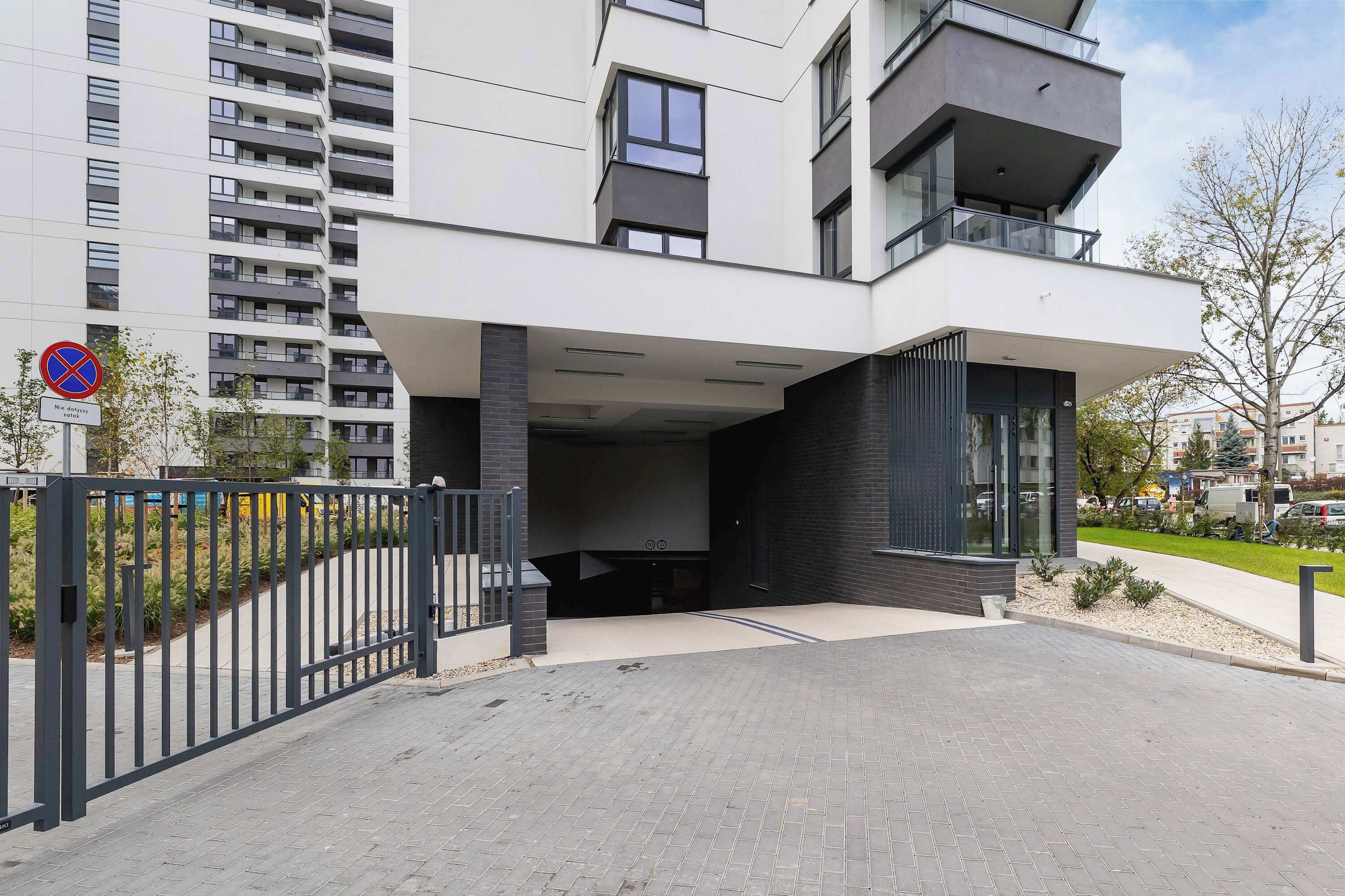 Un edificio residencial moderno de varios pisos con entrada protegida y un letrero de no estacionamiento.
