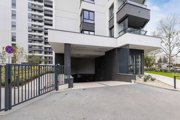 Un edificio residencial moderno de varios pisos con entrada protegida y un letrero de no estacionamiento.
