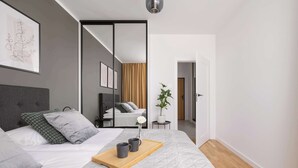 Un dormitorio moderno con cama, mesita de noche, espejo y planta en maceta.