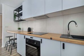 Een koelkast, een oven, een kookplaat, kookgerei, borden en bestek