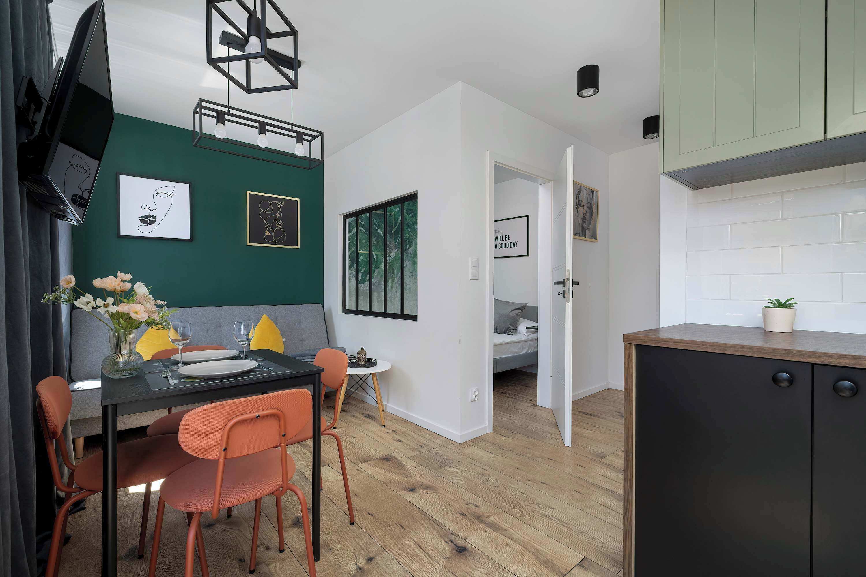 A compact living space with a dining area, kitchenette, and a bed in the adjacent room.