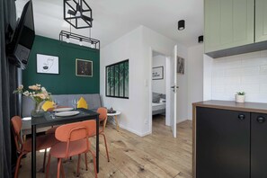 A compact living space with a dining area, kitchenette, and a bed in the adjacent room. - Stylish Apartment in the Center of Katowice | Balcony (Katowice)
