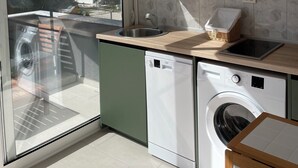 A modern kitchen with a built-in washing machine, a sink, and a window overlooking a residential area.